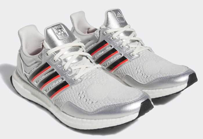 View of silver, black, and red adidas shoes.